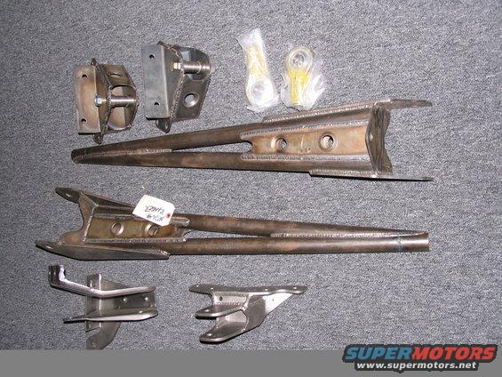Metal suspension components laid out on a gray surface, including control arms and brackets