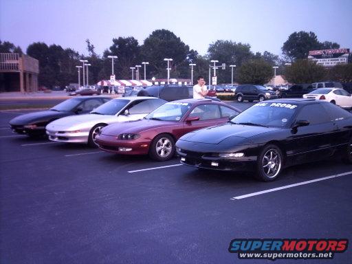 Four black, silver, and red Ford Probes parked in a lot, with "FORD PROBE" text on the windshield of the front car