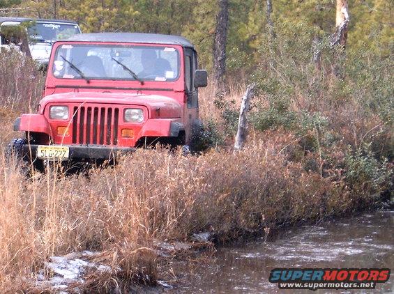Red Jeep Wrangler with license plate SLG 227 in off-road terrain