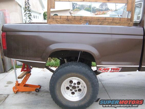 1985 Ford Ranger pickup truck bed with a large off-road tire and 'Kar Tek Off Road' sticker