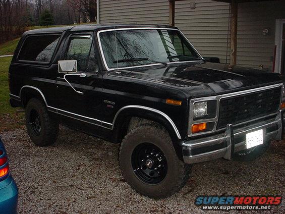 1983 Ford Bronco parked on gravel in front of a house