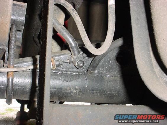 Close-up of a vehicle's rear axle and suspension with brake lines and a U-bolt