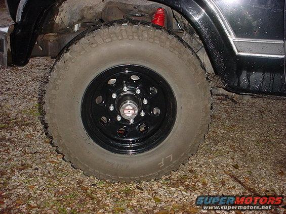 Close-up of a black Bronco wheel with a red shock absorber visible above it