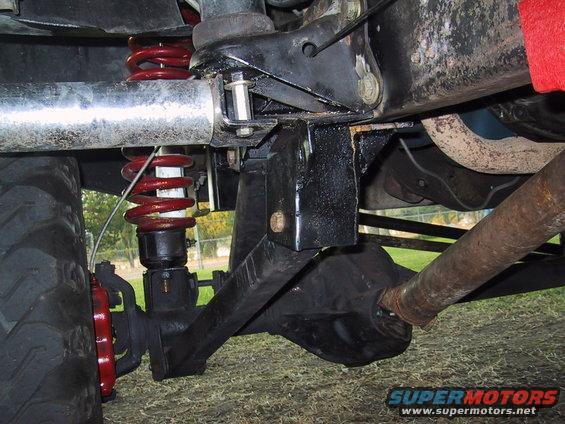 Undercarriage view of a vehicle's suspension with red coil springs and a large tire