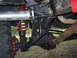 1990 Ford Bronco - Close-up view of the suspension system and undercarriage of a vehicle, showing red coil springs and a large tire.
