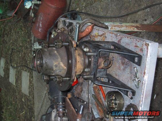 Close-up of a vehicle's front hub assembly and bracket, with tools scattered around