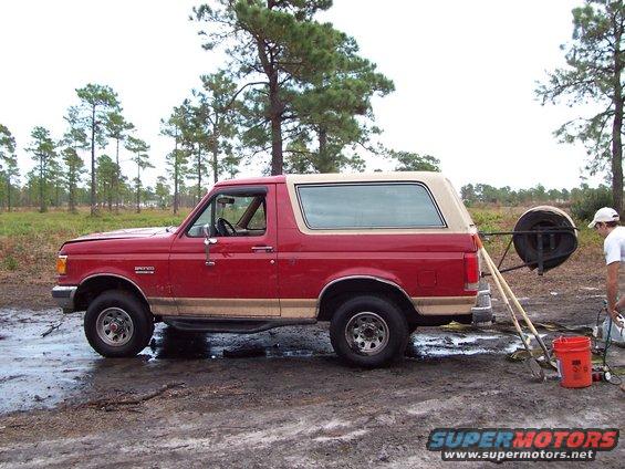 1989 Ford Bronco parked on muddy ground with a spare tire mounted on the rear carrier