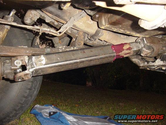 close-up of vehicle's driveshaft and suspension components, with grease visible on the driveshaft