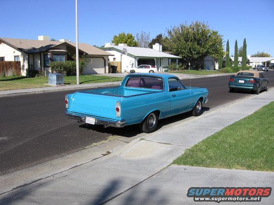 1966 Ford Ranchero parked on suburban street, rear view. Green convertible in background