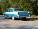 1956 Chevrolet Biscayne - Rear view of a classic two-tone blue Chevrolet sedan parked in a lot with trees.