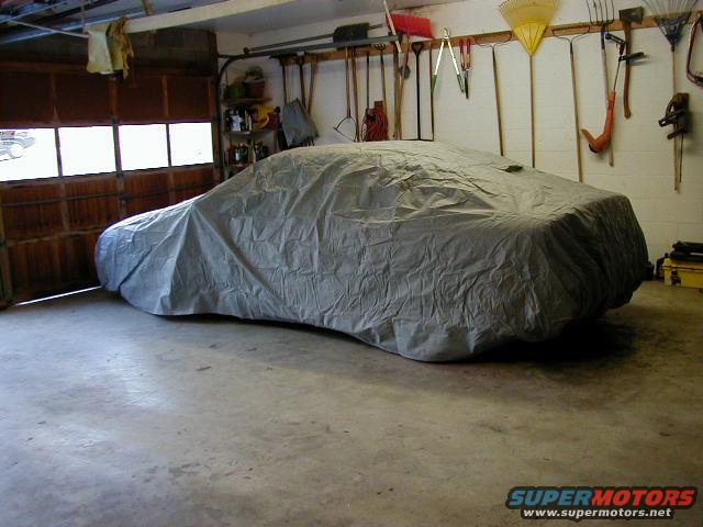 Car covered by a gray car cover in a garage