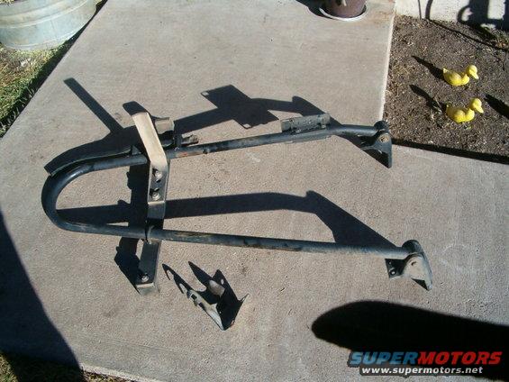 Black spare tire rack with strap, lying on concrete