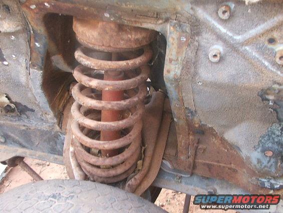 Close-up of a heavily rusted coil spring and shock absorber assembly, part of a car's suspension