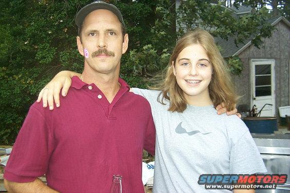 Man and girl smiling outdoors with a building in the background