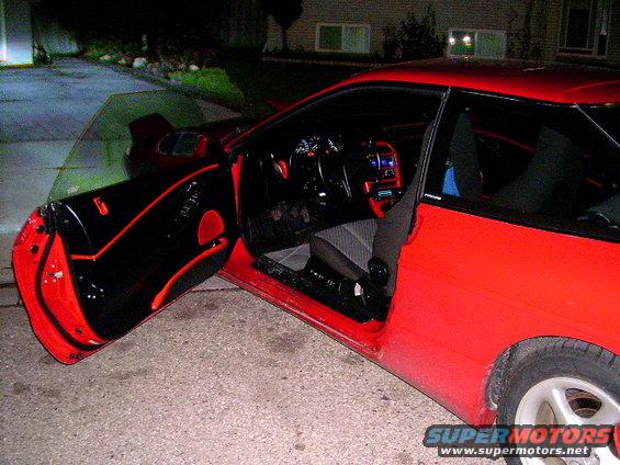 Red car interior with black door panels and red trim, driver's door open