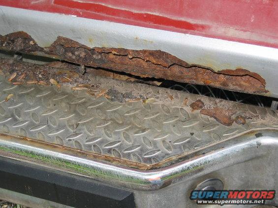 Close-up of heavily rusted metal trim and diamond plate on a vehicle's lower body