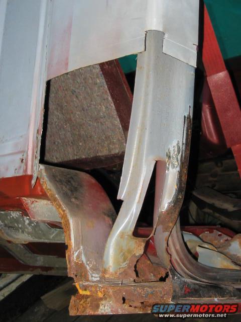 heavily rusted metal frame and body panel sections of a vehicle, showing structural damage