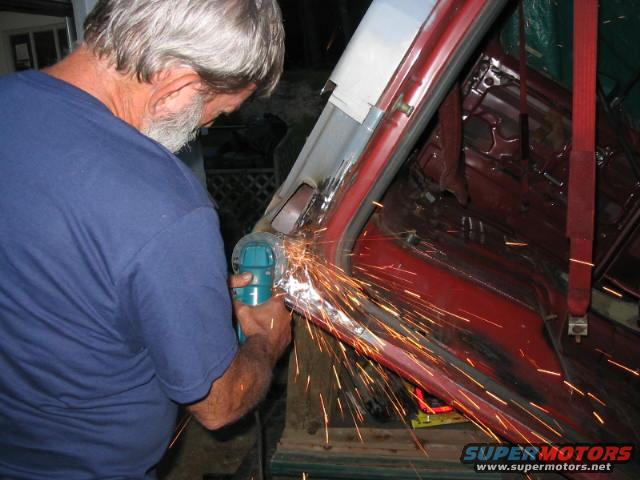 Man grinding metal inside red vehicle interior with sparks flying