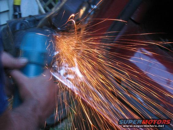 Close-up of sparks flying from a blue grinder on red metal