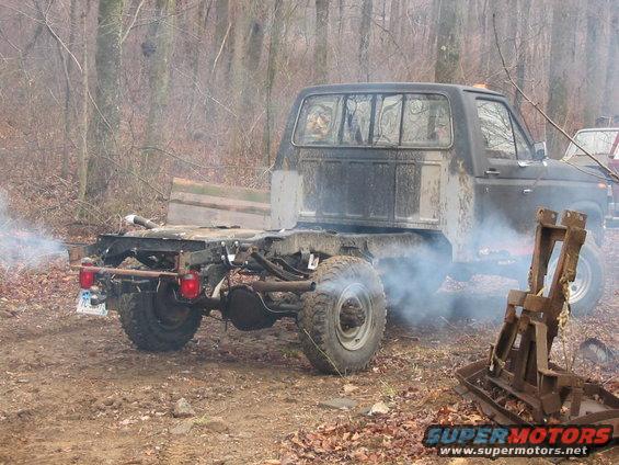 Rear view of a 1985 Ford F-350 pickup truck with exposed frame and exhaust emitting smoke