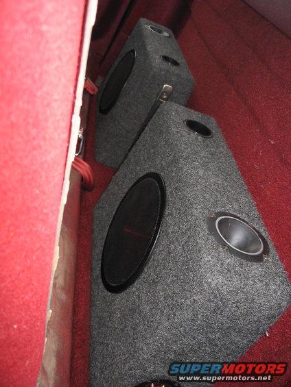 Gray carpeted speaker boxes with black woofers in red interior