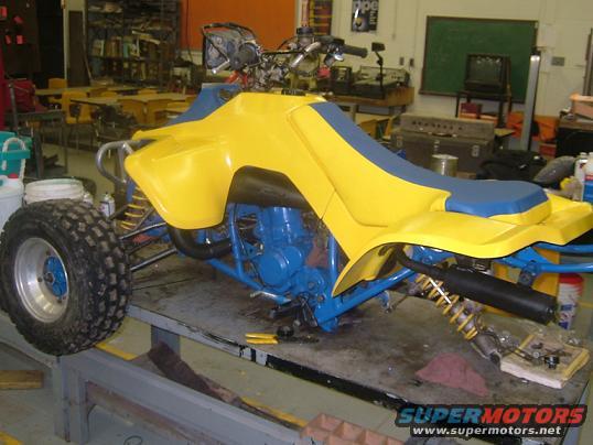 Yellow and blue ATV on a workbench, looks like it's being worked on