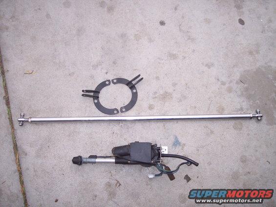 Car antenna assembly with chrome mast, mounting bracket, and motor unit laid out on concrete