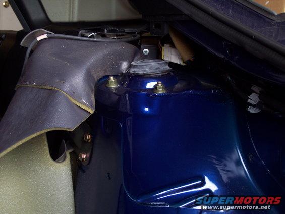 Blue car's strut tower with visible bolts and wiring. Supermotors.net logo visible