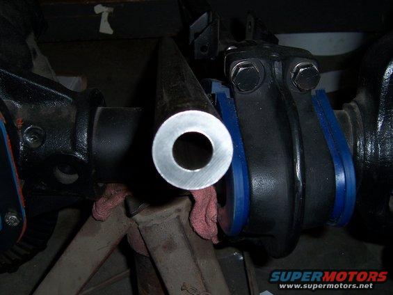 Close-up of a metal rod end with a hole, connected to black steering components with blue bushings