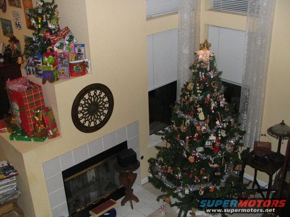 Christmas tree decorated with ornaments and tinsel next to a fireplace