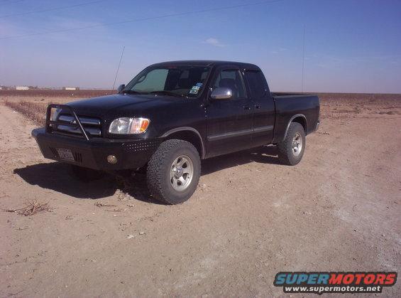 Black 2003 Toyota Tundra pickup truck with aftermarket bumper and bull bar parked on a dirt road
