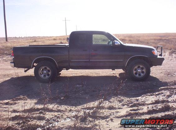 Dark pickup truck parked on dirt road. It has a single cab and a long bed