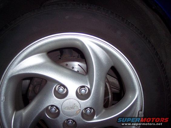 Close-up of a silver alloy wheel with a Ford logo in the center, showing a brake rotor behind it