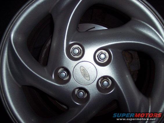 Silver five-spoke Ford wheel with a visible Ford logo and brake rotor