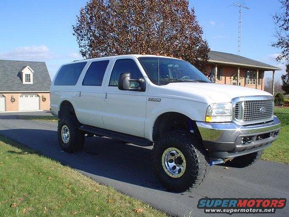 White Ford Excursion with lifted suspension and large tires parked in a driveway