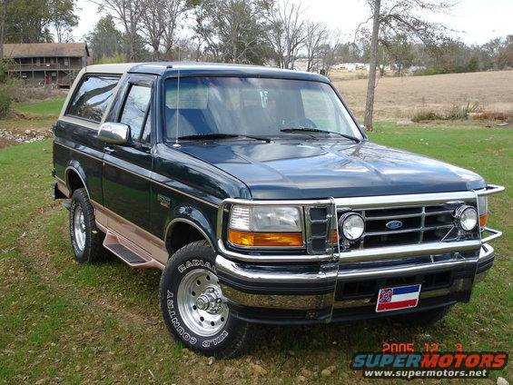 Dark green Ford Bronco with tan trim and a brush guard parked on grass