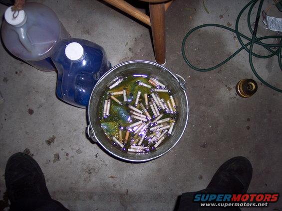 Bucket of cigarette butts in murky liquid, with plastic jugs and a chair leg