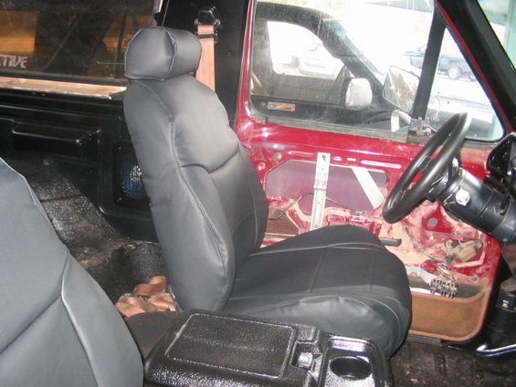 Interior shot of a vehicle with black seats, exposed door panel, and steering wheel