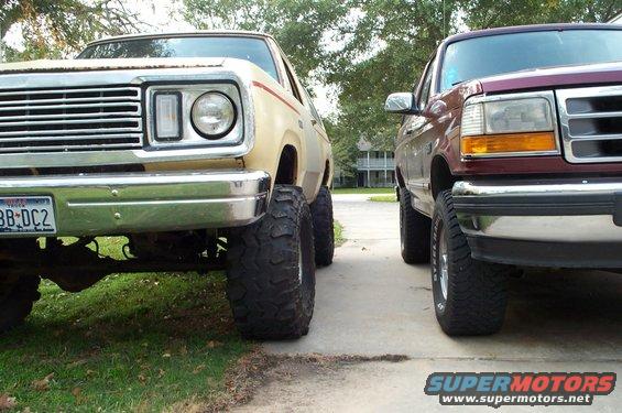 1978 Dodge Power Ram front end with chrome grille and large tires, parked next to a maroon Ford truck