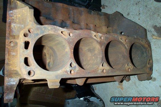 Rusty engine block with four cylinders visible, viewed from the side