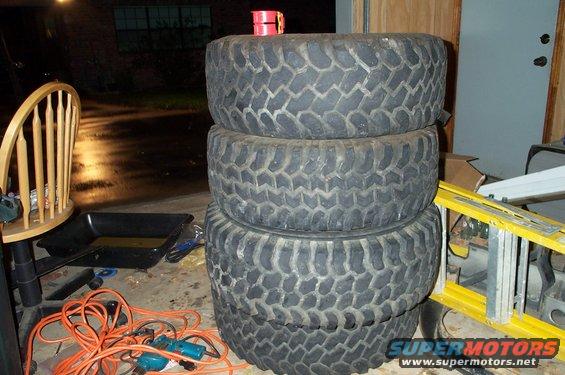 Stack of four large, knobby off-road tires with visible tread patterns