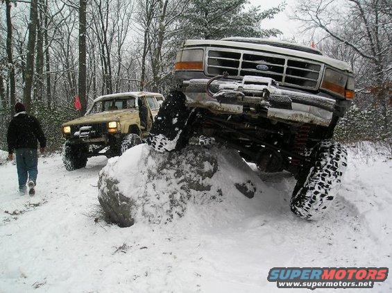 Ford Bronco stuck on a rock in the snow with another off-road vehicle behind it