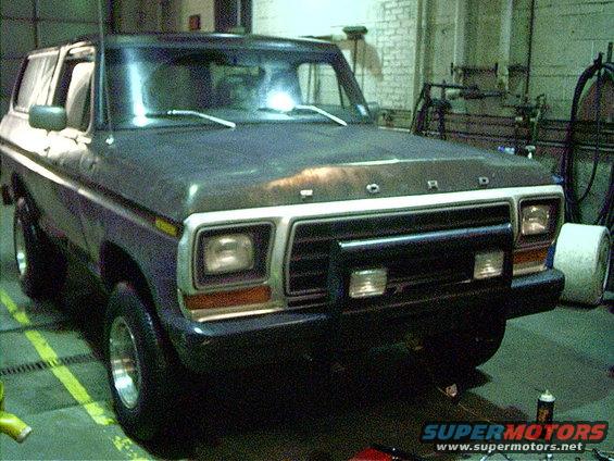 Dark blue Ford Bronco with a black bull bar and chrome wheels, seen from a 3/4 front angle
