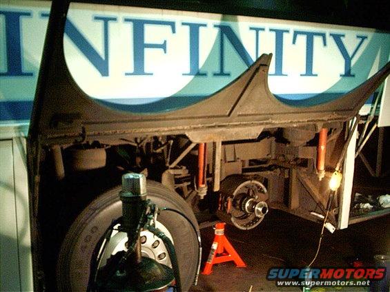 Undercarriage of a bus with suspension and brake components visible. The word INFINITY is on the side