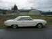 1993 Ford Bronco - A white coupe is parked on a wet asphalt surface with a fence and buildings in the background.