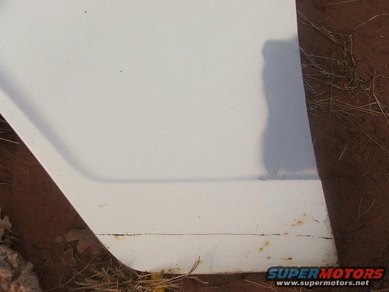 White car door edge showing rust and dirt on the lower trim