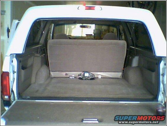 White Ford Bronco interior cargo area, rear seats folded down, showing carpeted floor and side panels