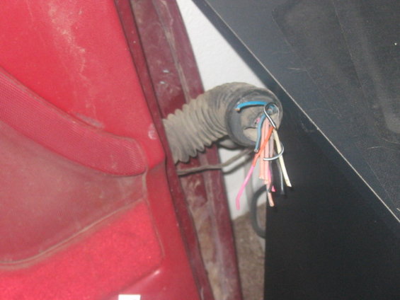 close-up of a red interior panel with a gray corrugated conduit holding exposed wires