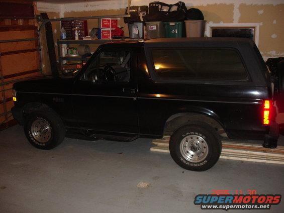 Black SUV parked indoors, side view. Visible text on tire