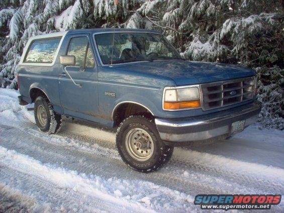 1992 Ford Bronco parked on a snowy road with trees in the background
